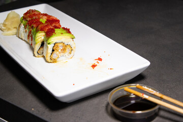 Close up of sushi roll with fried shrimp inside and fresh avocado and salmon on the top