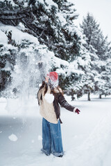 Young woman having fun with snow on a winter day in the park.  Concept of fun, relaxation, winter holidays.