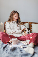 Young woman with dog drinking warm coffee at home