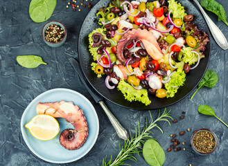 Grilled octopus with salad on a plate.