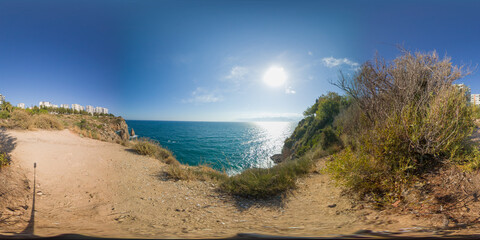 A breathtaking coastal view with clear skies and the sun shining over the blue ocean in a...