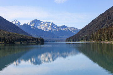 mountains are reflected in the smooth surface of duffey lake, british columbia