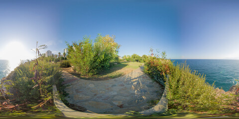A peaceful coastal garden with lush greenery overlooking the ocean, captured in a 360-degree...