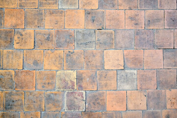 Orange brown white beige old shabby worn out floor tiles with damages cracks dirt caverns potholes and paint stains. Art retro grunge design background texture.