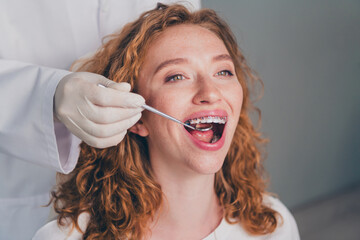 Photo of professional dentist examining teeth of patient with tool in clinic