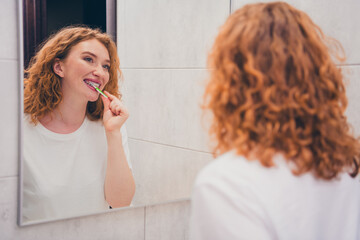 Photo of happy charming girl preparing for sleep brushing teeth at home in evening daily teeth...