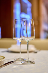 Christmas festive modern restaurant interior with greenery, pleasant cozy lighting and festive table setting with glasses.