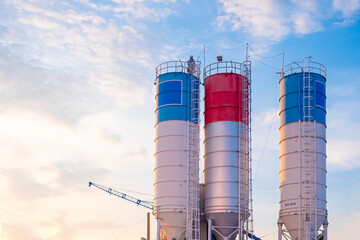 Cement storage silos in industry manufacturing factory area against blue sky in evening time