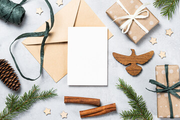 Festive composition with an envelope, blank card, pine branches, gifts, and craft elements. The eco-style and natural materials create a cozy atmosphere for Christmas and New Year greetings.