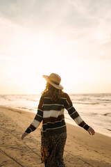 Beautiful woman at the windy day walks along the beach and enjoys the autumn weather. Travel, weekend, relax and lifestyle concept.