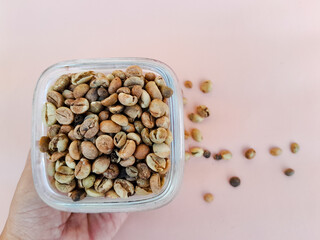 Coffee beans are placed in a glass bowl and held in hand. Raw coffee beans. Coffee beans. Shot from top view