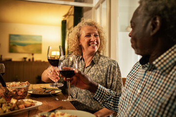 Happy senior couple enjoying dinner and wine at home