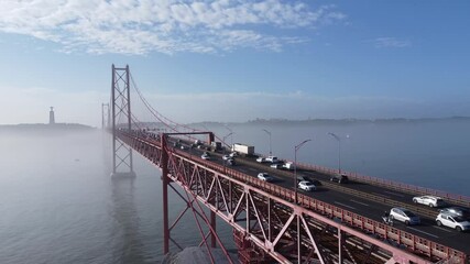 A Ponte 25 de Abril ergue-se majestosamente sobre as águas brilhantes do Rio Tejo, com a sua estrutura vermelha icônica resplandecendo sob o sol intenso. 
