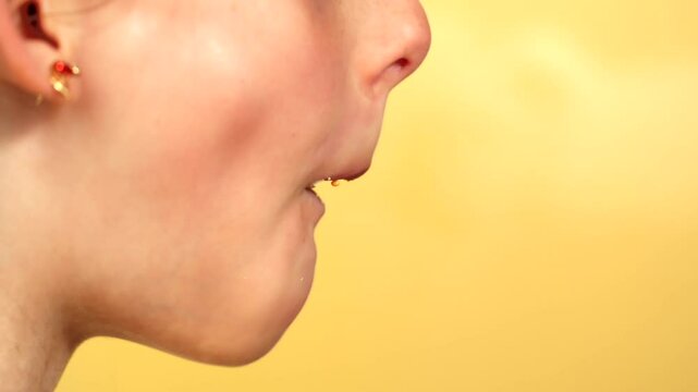 Cute Child eating donut in front of yellow background. Young girl eat doughnut while having fun and doing silly faces. Filmed in side profile, Pro Res 4k UHD.