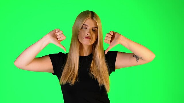 Pretty Blonde Woman Thumbs Down Gesture, Studio Portrait With Green Background