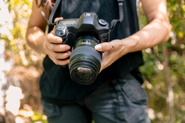 Unrecognizable Woman Holding a Digital DSLR Camera Outdoors. Midsection close-up
