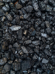 Coal. The dark texture is black. Background image of anthracite coal. A grade of high-quality metallurgical coal anthracite. The surface of natural black coal. Black background. Vertical image.