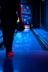This photo shows a bowler getting ready to throw a strike. The blue bowling ball is held firmly in...
