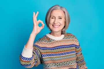 Portrait of optimistic senior person with bob hairdo wear ornament pullover showing okey winking...