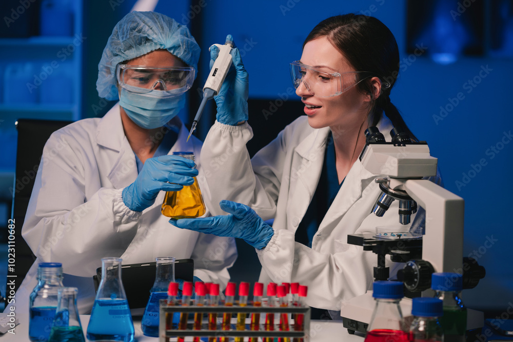 Wall mural team of biochemical research scientists working with a microscope for vaccine development