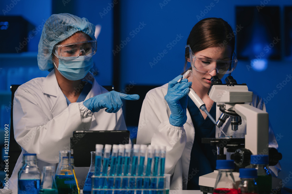 Wall mural team of biochemical research scientists working with a microscope for vaccine development