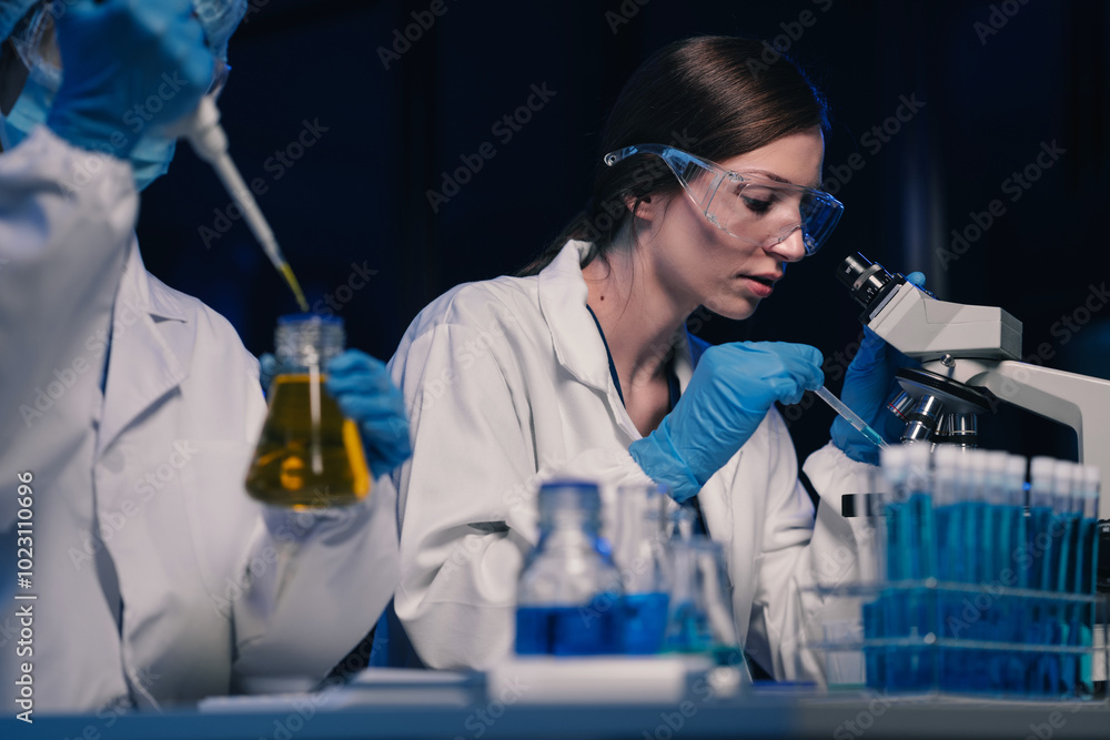 Wall mural team of biochemical research scientists working with a microscope for vaccine development