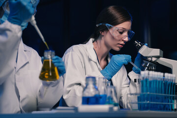 Team of biochemical research scientists working with a microscope for vaccine development