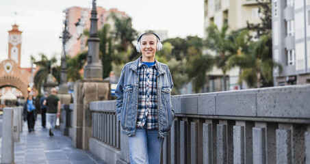 Young bald woman listening music playlist with city in background - City lifestyle and autumn season concept - Focus on face