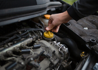 A man's hand holds the lid. checking the oil level.