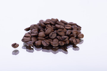 Coffee beans on a mirror with white background, highlighting their texture, color, and the reflection effect
