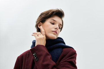 A beautiful woman showcases her stylish winter outfit while gently touching her face.