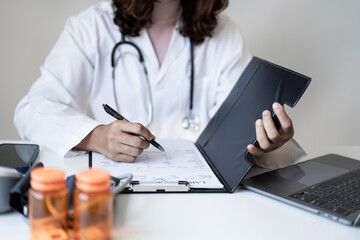 Female doctor holding a medicine bottle is checking the quality of medicine for any side effects the patient or not and recording patient information at the hospital. medical and health care concept