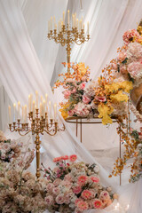 Elegant interior decor with white seating, golden candelabras, and floral arrangements