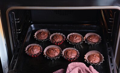 Taking chocolate nut muffins out of the oven in brown tins. Cooking, baking. Recipes chocolate.