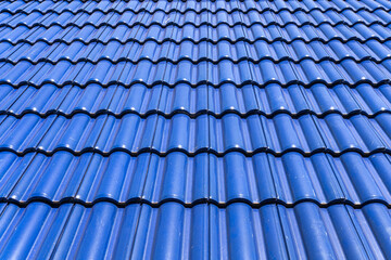 metal tiles cover the rooftop of a new house, creating a textured pattern against the blue sky