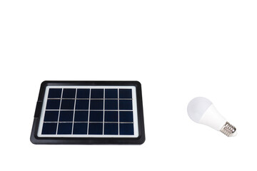 Portable solar panel lies next to light bulb on transparent background (close-up). Renewable green...