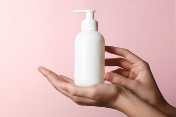 Woman with shampoo bottle on pink background, closeup