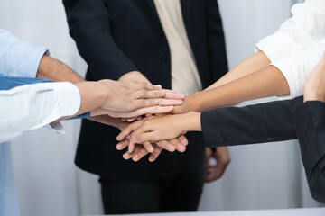 Fototapeta premium Group of diverse office worker join hand together in office room symbolize business synergy and strong productive teamwork in workplace. Cooperation and unity between business employee. Prudent
