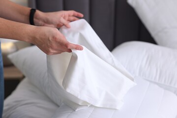 Woman changing clean bed linens at home, closeup