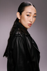 Naklejka premium Fashion, asian beauty, woman, black leather jacket, posing, hands on hips an attractive asian woman wearing a stylish black leather jacket strikes a pose for the camera
