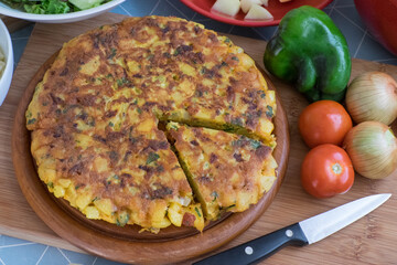 Tortilla de patatas e ingredientes sobre una tabla de cocina