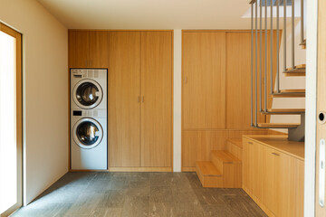 Laundry room with large wooden closets and rock floor. There is a staircase on the right that leads to the living room. No one inside