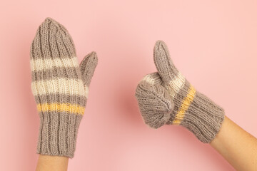 Knitted warm mittens worn on hands that show gestures