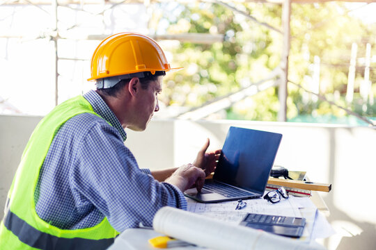 Caucasian Male architect engineer construction worker using computer laptop working on blueprint design plan using pencil tool analyzing design innovation building landscape housing architecture.
