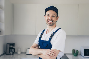 Confident handyman in kitchen ready for home renovation in overalls and cap