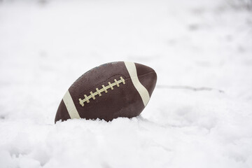 a football covered with snow and laying in the snow