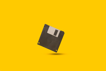 A floppy disk floating on a yellow background with copy space