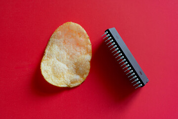 Conceptual contrast of a microchip and potato chip symbolizing the interplay between technology and nature on a bold red background. Concept.