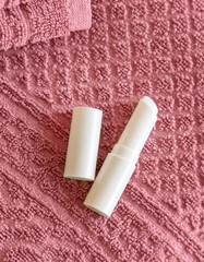 Opened lip balm stick on pink towels top view, lid mockup. Skincare beauty product