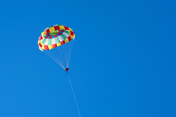 Tourists fly on a bright paraglider against the blue sky in the summer on a sunny day. Beach...